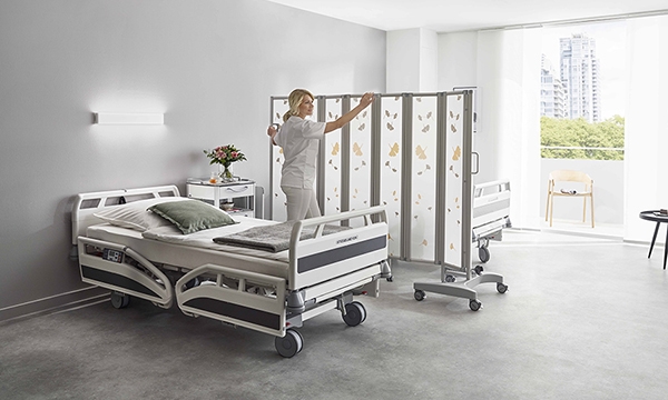 ropimex Sichtschutz fahrbare Faltwand Modell RFW - Krankenschwester öffnet die mobile Faltwand zwischen 2 Krankenbetten