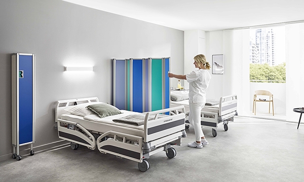 ropimex Paravent rigide Modèle RFW en chambre à plusieurs lits - l'infirmière ouvre un paravent rigide